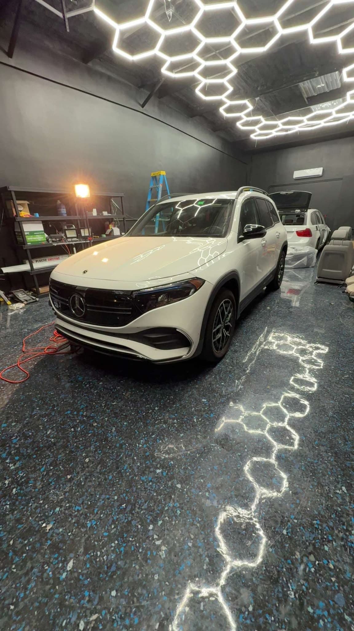 A Mercedes-Benz SUV finished with Formula 1051 under the shop's hexagon light rig