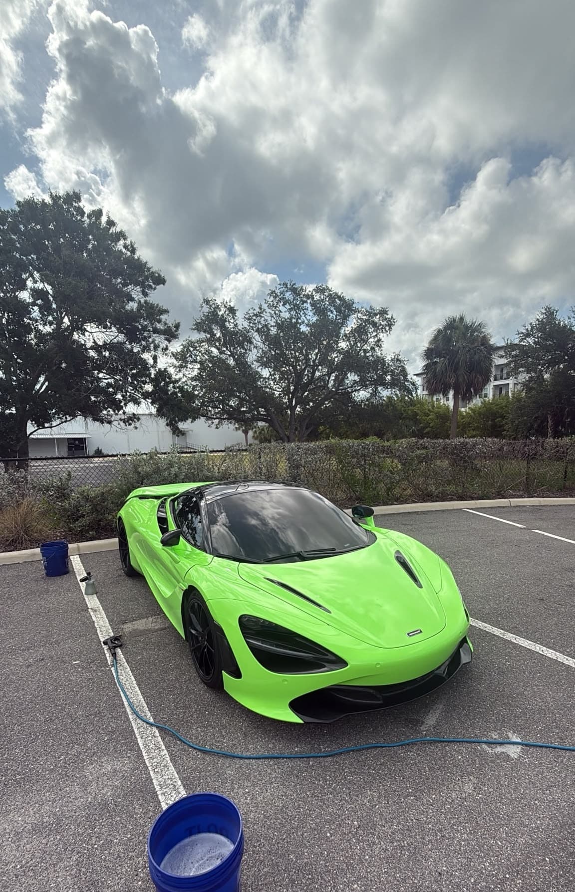 A lime green supercar mid hand-wash, suds still clinging to the coated paint
