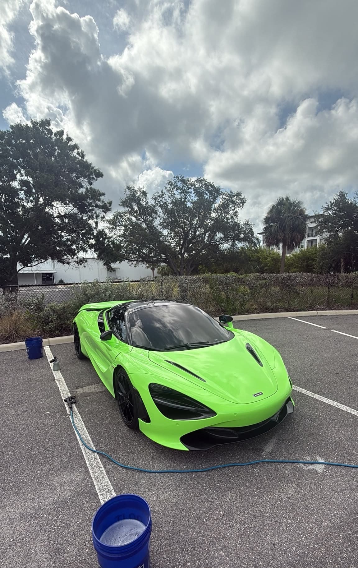 Two-bucket hand wash underway on a lime-green supercar, our rig set up in the client's lot